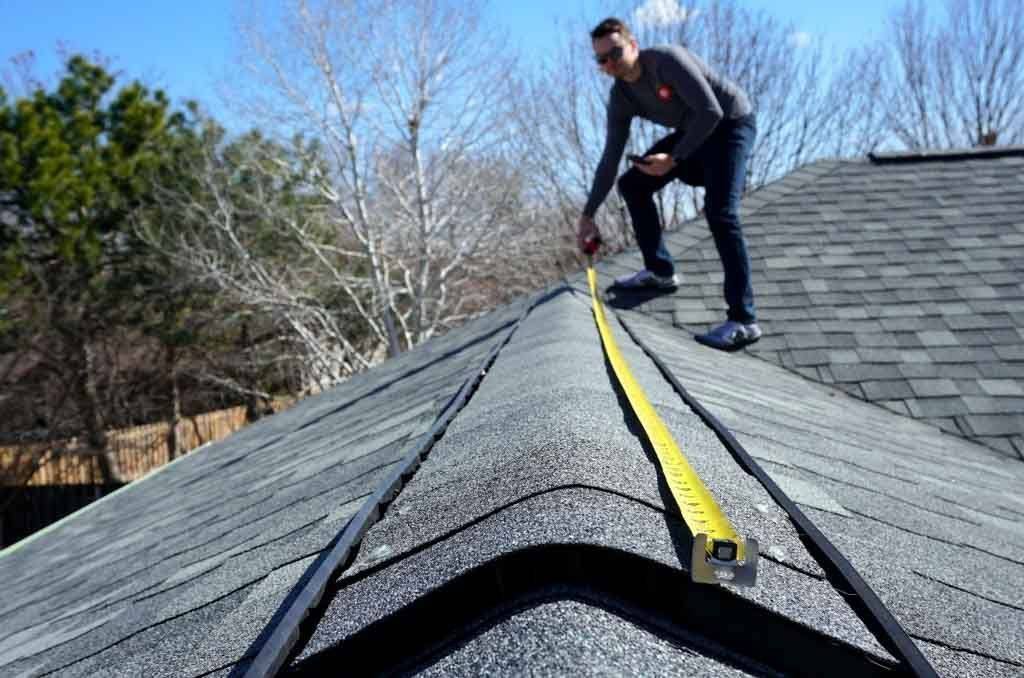 Roofer measuring a roof before repair work